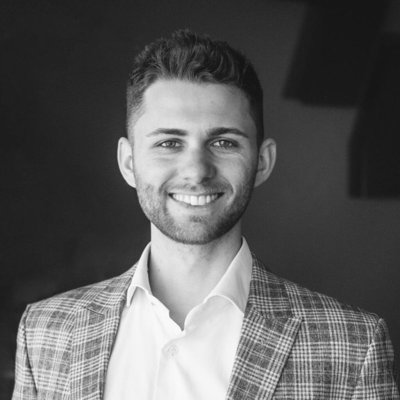 A black and white photo of a smiling man in a suit for web design company in Wien.